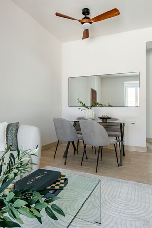 A modern dining area with a ceiling fan, a dining table with chairs, a large mirror, and a decorative plant. - Charming 2-bedroom apartment in La Latina (Madrid)