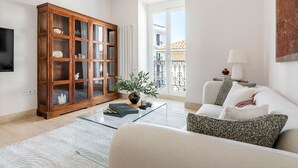 Un salon moderne avec un meuble en bois, une table basse en verre, un canapé blanc et une vue sur un balcon.