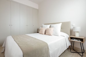 A minimalist bedroom with a bed, pillows, a bedside table with a lamp, and a wardrobe. - Charming 2-bedroom apartment in La Latina (Madrid)