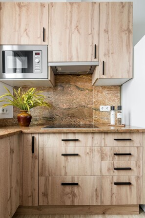 Eine Küche mit Holzausstattung, einer Mikrowelle, einer Arbeitsplatte aus Granit, einer Pflanze und Salzbehältern.
