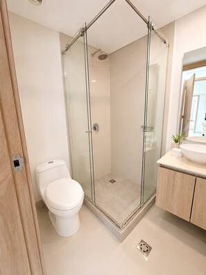 Une salle de bain moderne avec une douche à parois de verre, des toilettes et un meuble-lavabo avec un évier.