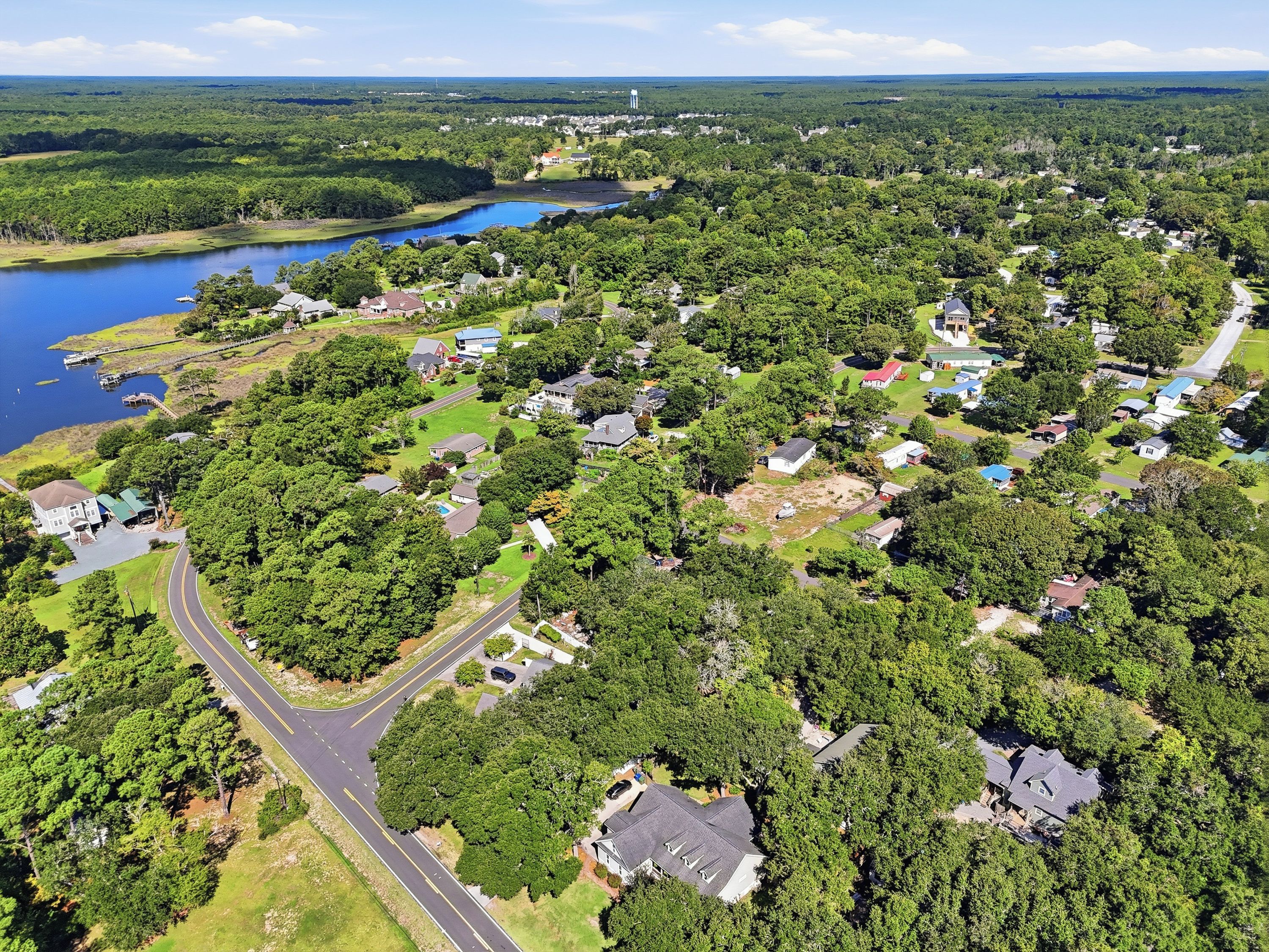 Vue aérienne d’un quartier résidentiel avec des maisons, une route et un lac.