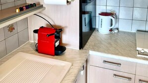 Uma cozinha compacta com cafeteira, chaleira e micro-ondas.