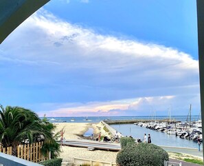 Un port de plaisance avec des bateaux, une plage de sable et un ciel dégagé.