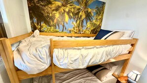 Uma cama beliche com um mural tropical ao fundo.