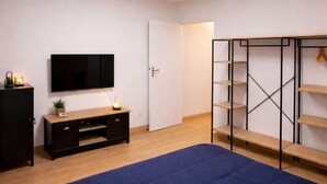 A bedroom with a bed, a TV, a wardrobe, and a desk. - Le Cocon de Sohën – A Cozy and Comfortable Two-Bedroom Apartment in Montréjeau (MONTREJEAU)