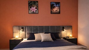 A bedroom with a large bed, two bedside tables with lamps, and two framed pictures on the wall. - Le Cocon de Sohën – A Cozy and Comfortable Two-Bedroom Apartment in Montréjeau (MONTREJEAU)