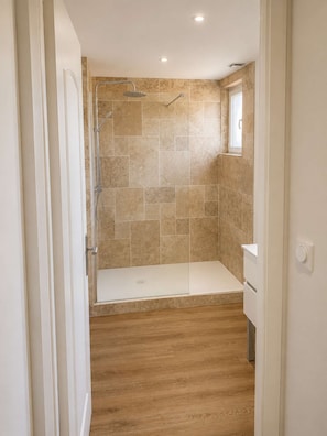A bathroom with a shower, tiled walls, a wooden floor, and a window. - L'Échappée d'Ilhonn – Cozy, self-contained studio in Mazamet (Mazamet)