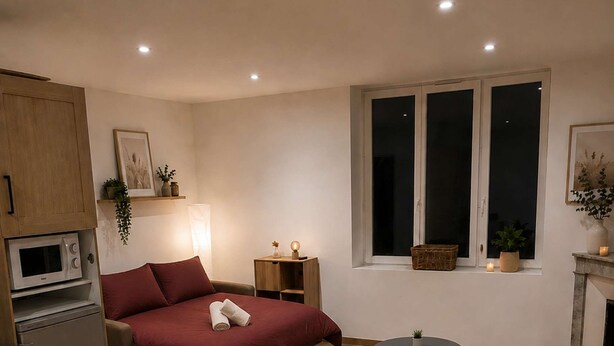 Un espacio habitable compacto con cama, mesa de comedor, una pequeña cocina y ventana con vistas.