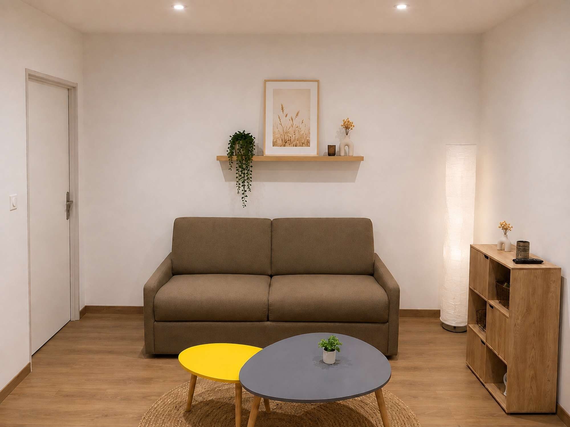 Een woonkamer met een bank, een klein tafeltje, een lamp en een boekenkast.