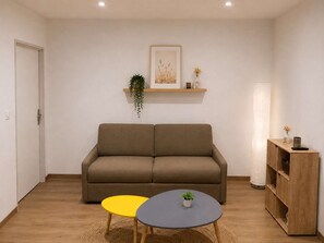 A living room with a sofa, a small table, a lamp, and a bookshelf.