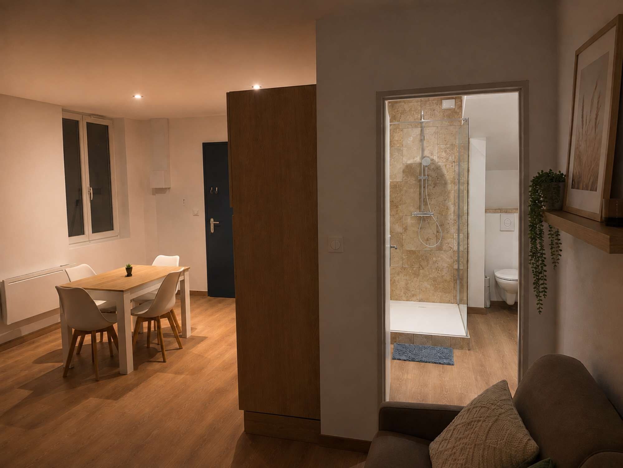 Un salon moderne avec un coin repas, une porte vitrée donnant accès à une salle de bain et une plante fixée au mur.