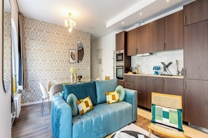 Un salon moderne comprenant un canapé, une table basse et un coin repas avec des chaises.