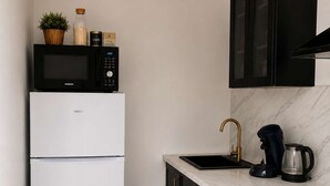 Cocina compacta con refrigerador, microondas, estufa, pileta y gabinetes negros.
