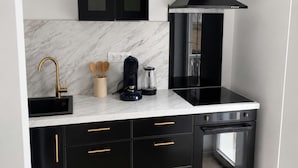 Una cocina moderna con armarios negros, encimera de mármol, horno empotrado y campana extractora negra.