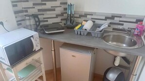 Eine kleine Küche mit Mikrowelle, einem Kühlschrank, einer Spüle und einem Geschirrgestell.