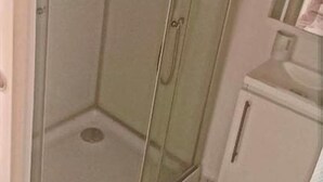 Eine gläserne Duschkabine mit einem weißen Schrank und einem Spiegel.