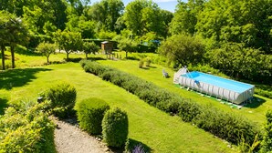 Un jardín cuidado con piscina, setos recortados y una pequeña construcción.