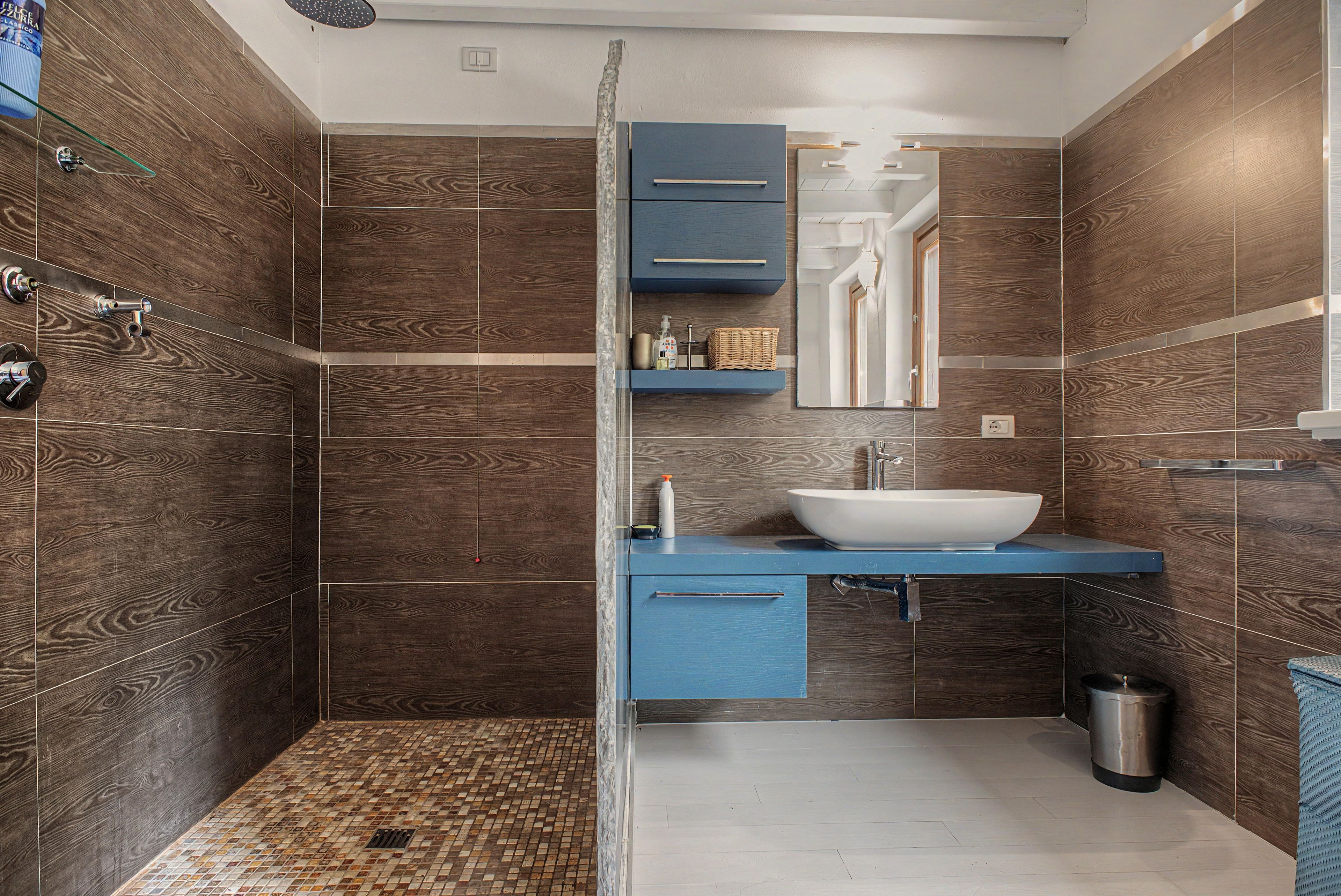 Une salle de bain avec douche, lavabo et meubles de rangement.