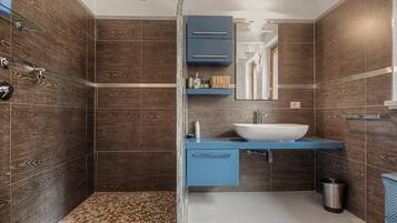 Une salle de bain avec douche, lavabo et meubles de rangement.