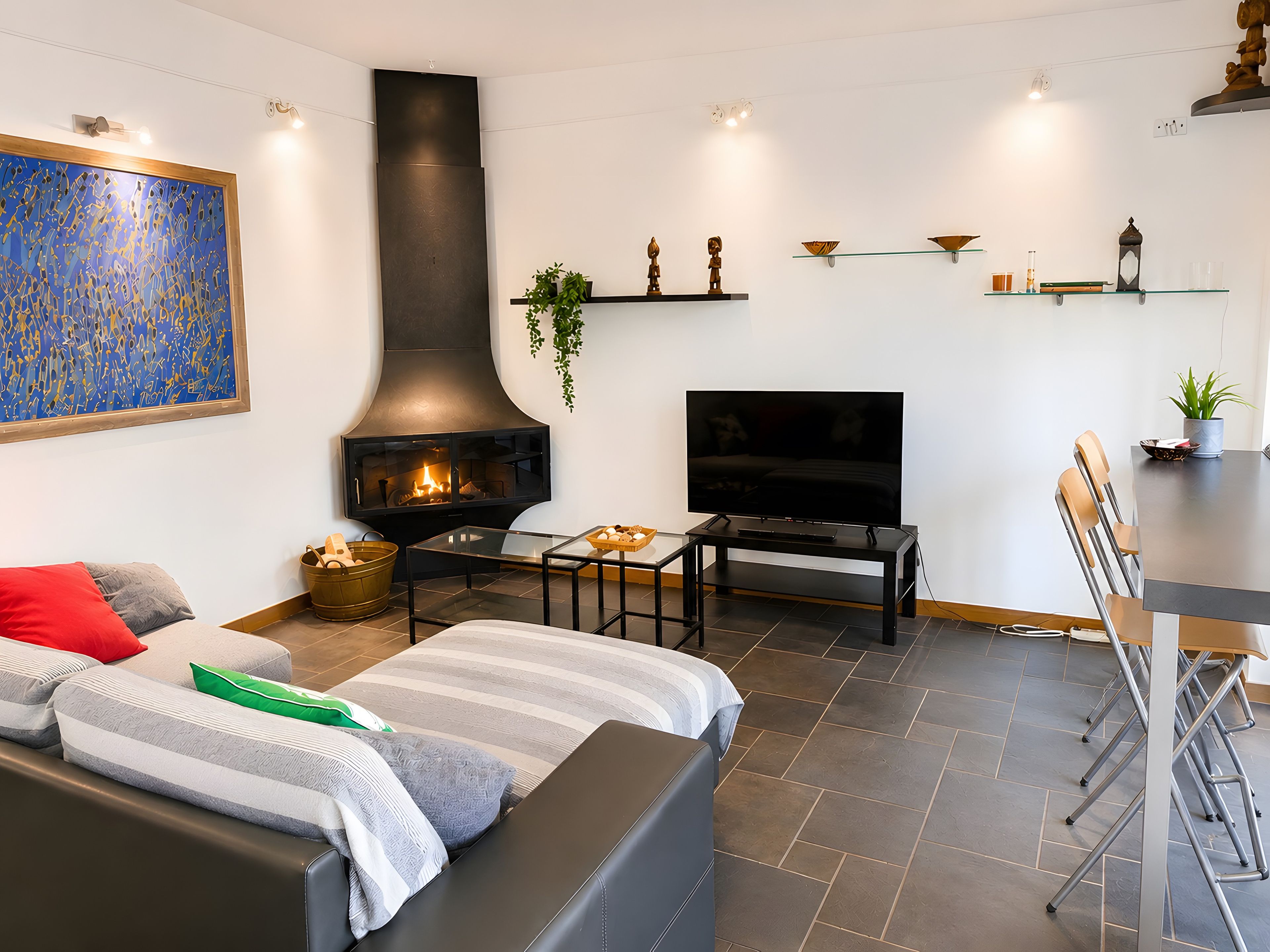 Una sala de estar moderna con chimenea, televisor de pantalla plana, comedor con sillas y una mesa de centro.