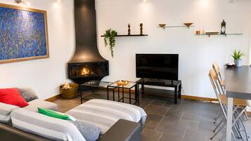 Una sala de estar moderna con chimenea, televisor de pantalla plana, comedor con sillas y una mesa de centro.