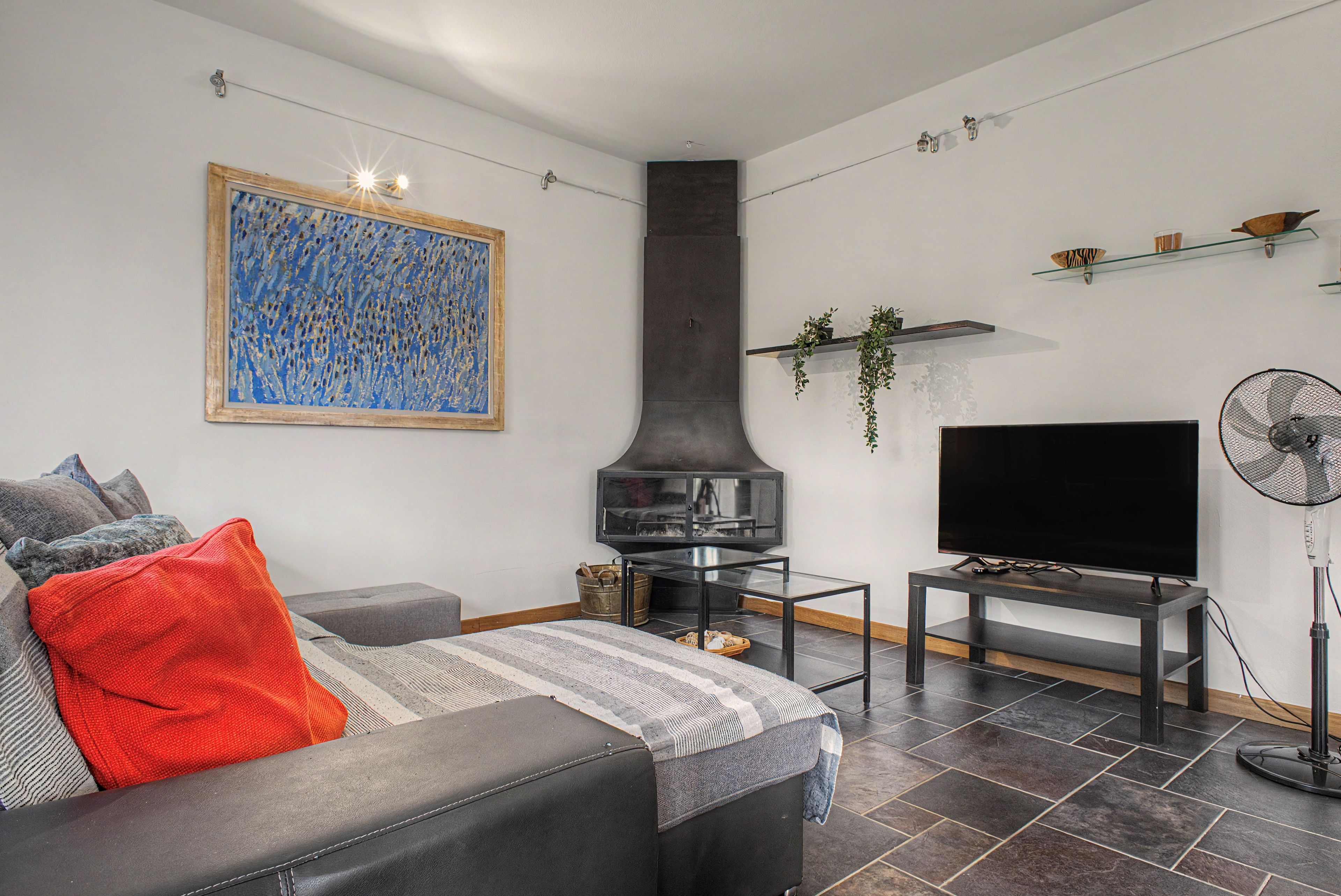 A living room with a sofa, a flat-screen TV, a fireplace, and a modern design.