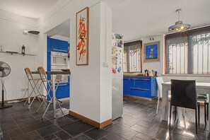 Eine moderne Küche mit blauen Schränken, einem weißen Kühlschrank und einem Essbereich mit Tisch und Stühlen.