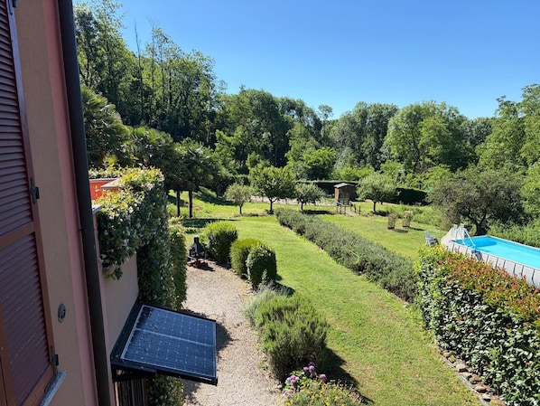 A landscaped garden with a swimming pool, solar panels, and a small gazebo. - Holiday Home 'Casa Le Sorgenti' with Shared Pool, Shared Garden and Wi-Fi (Cocquio-Trevisago)