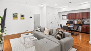 Ein modernes Wohnzimmer mit einem grauen Ecksofa, einem Couchtisch und einem Streifenmuster-Teppich.