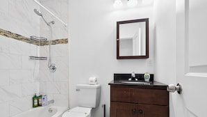 Ein Badezimmer mit Badewanne, Toilette, Waschtisch inklusive Spiegel und Dusche.