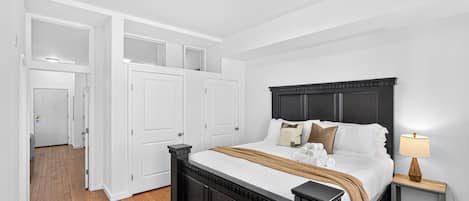 Un dormitorio con una cama grande, una mesita de noche con lámpara y un armario con espejo.