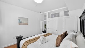 Ein Schlafzimmer mit einem Bett, einem Nachttisch, einem Kleiderschrank und einem Bild an der Wand.