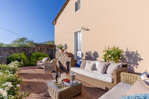 Eine Terrasse mit Korbmöbeln, einer Steinmauer und einem Blumentopf.