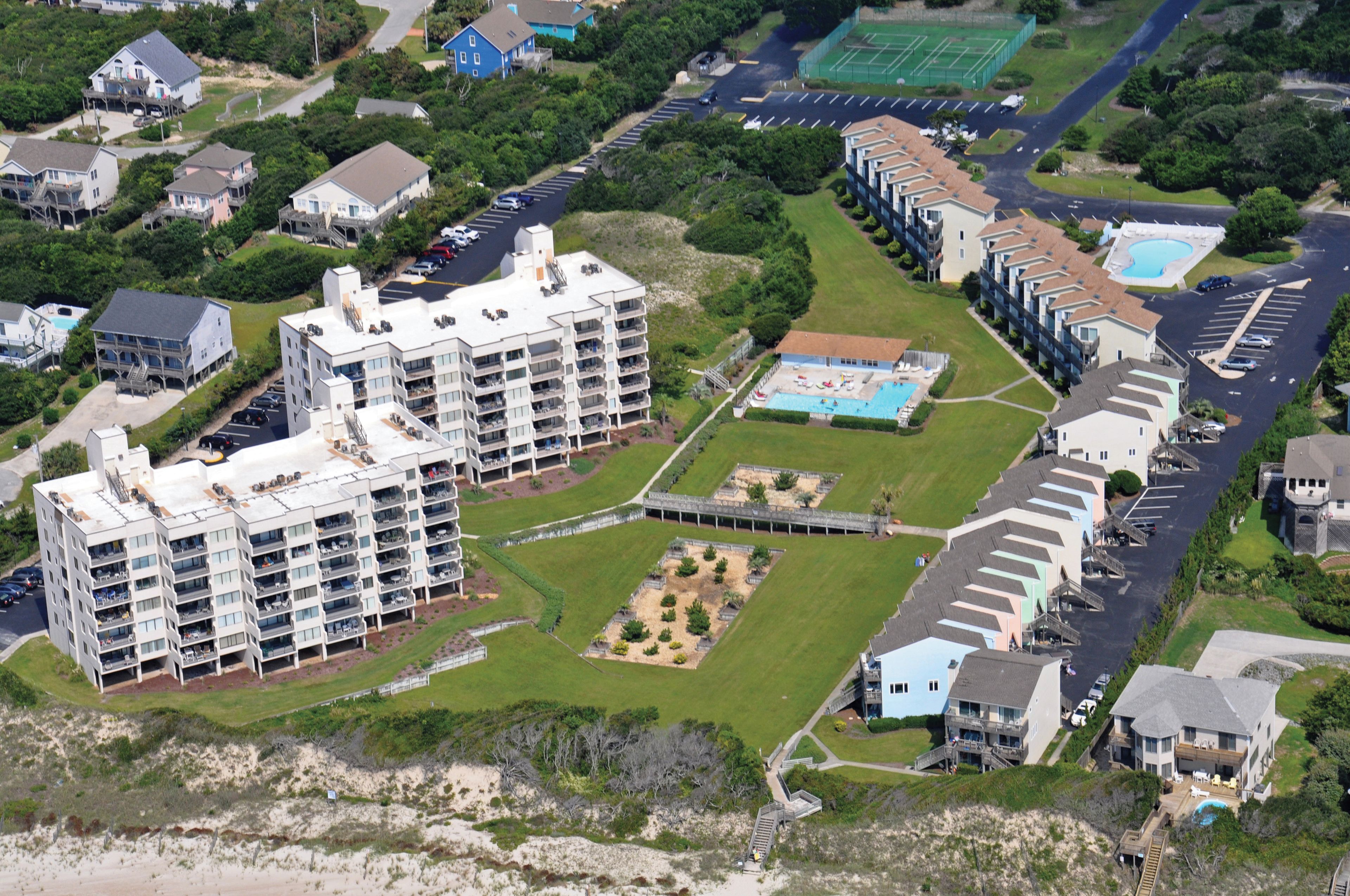 An aerial view of a residential area with multiple apartment buildings, a swimming pool, and a sports field.