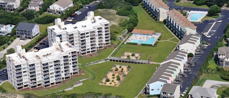 An aerial view of a residential area with multiple apartment buildings, a swimming pool, and a sports field.