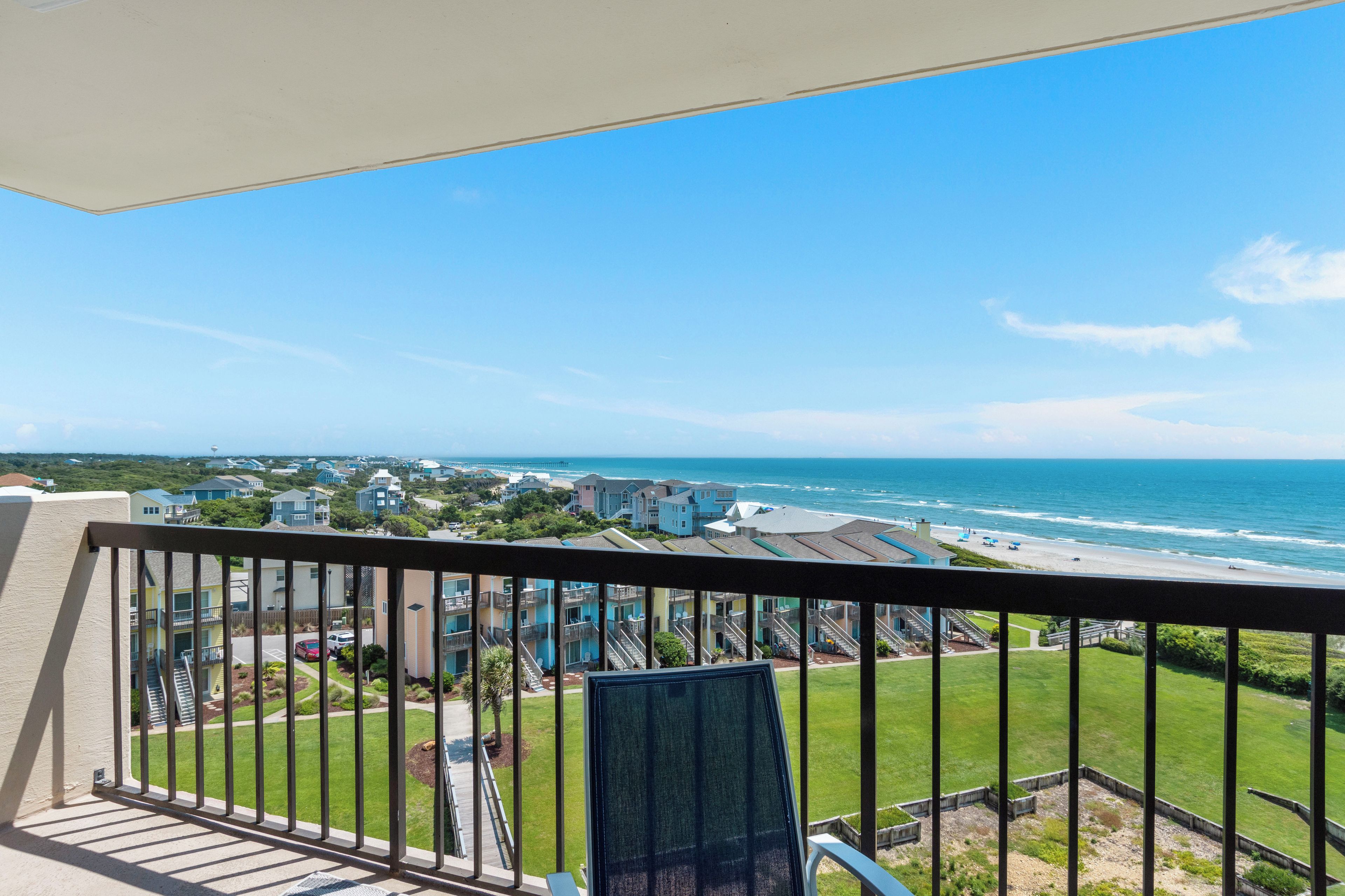 A balcony with a view of the ocean and a residential area.