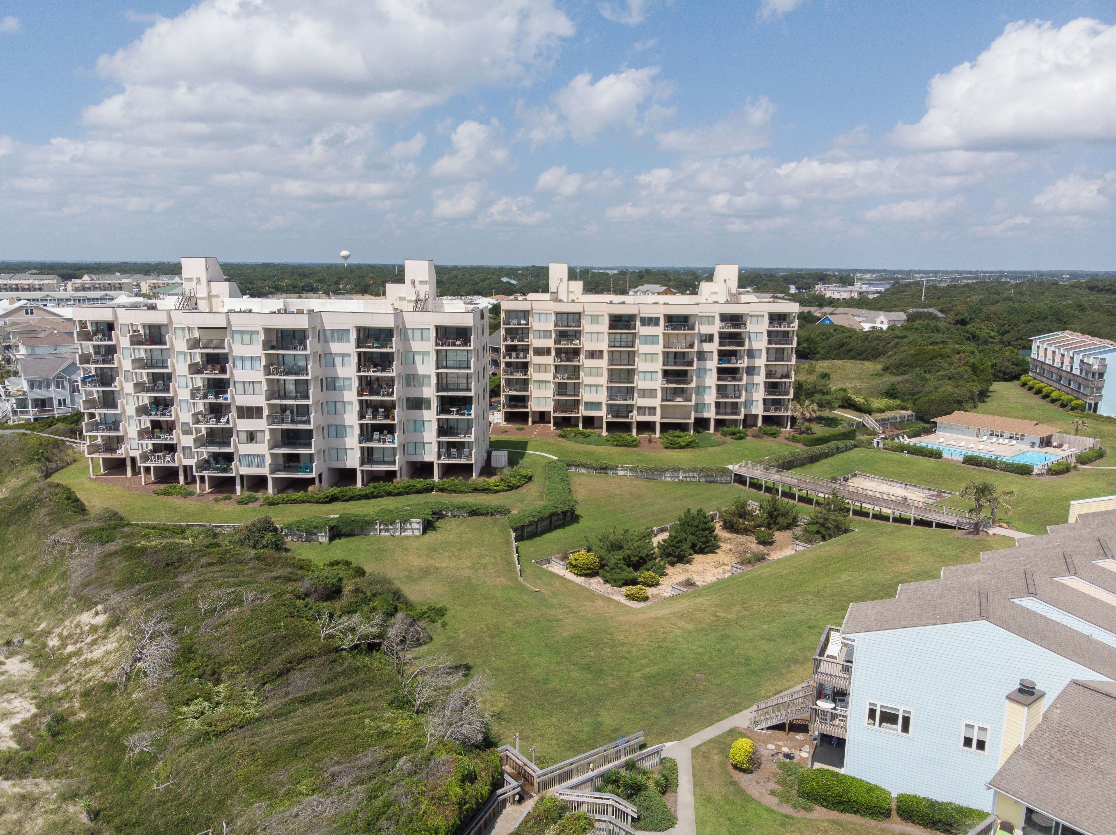 A modern apartment complex with multiple floors, balconies, and a swimming pool.