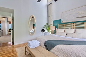 Een moderne slaapkamer met een groot bed, een nachtkastje, een spiegel en uitzicht op het omliggende landschap.