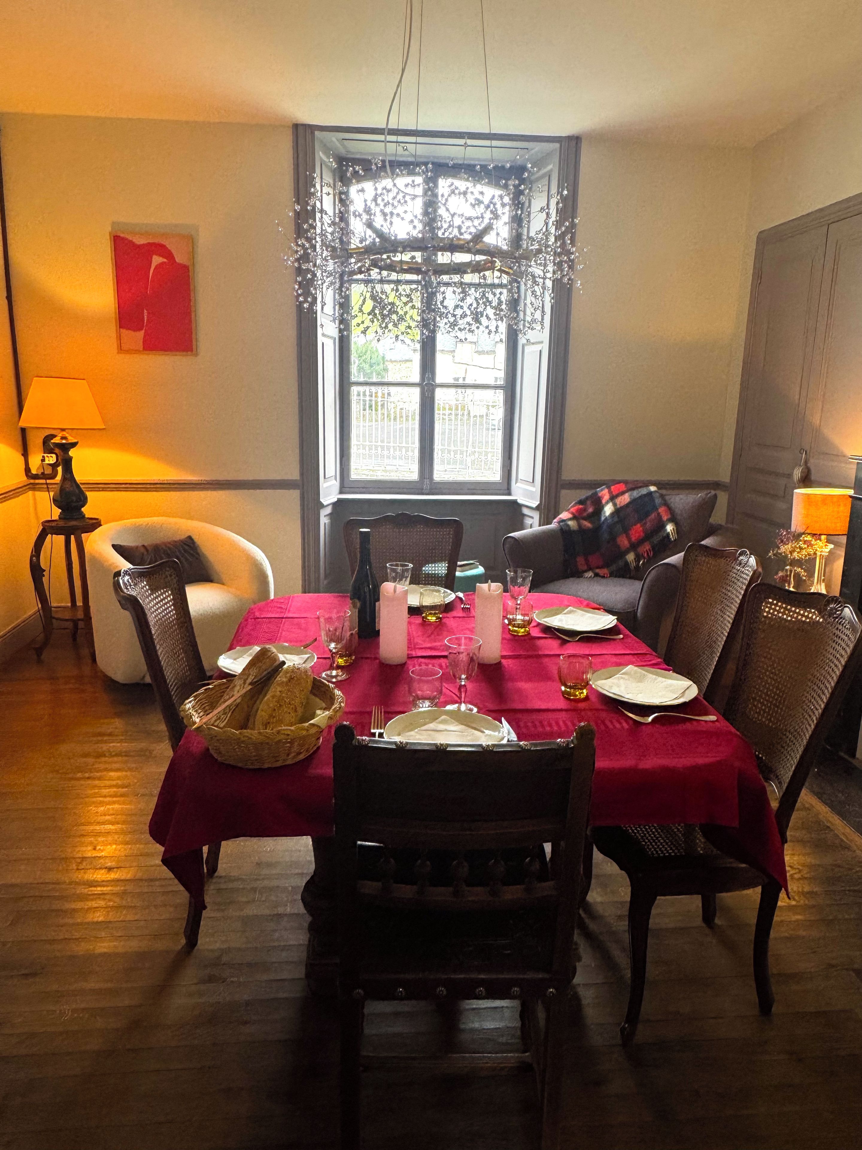 Un comedor con una mesa dispuesta para cuatro, una ventana con vistas y una lámpara a un lado.