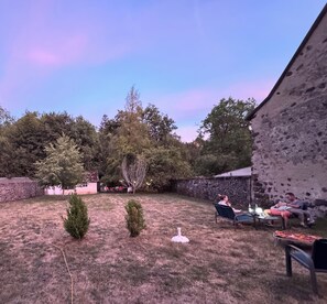 Ein Garten mit einer Steinmauer, einem kleinen Baum und einem Metalltisch mit Stühlen.
