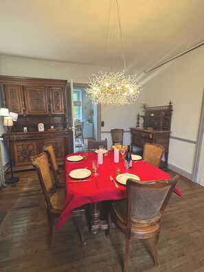 A dining room with a red tablecloth, wooden chairs, and a chandelier. - Maison Dellac – Les clés du temps (Saint-Saturnin)