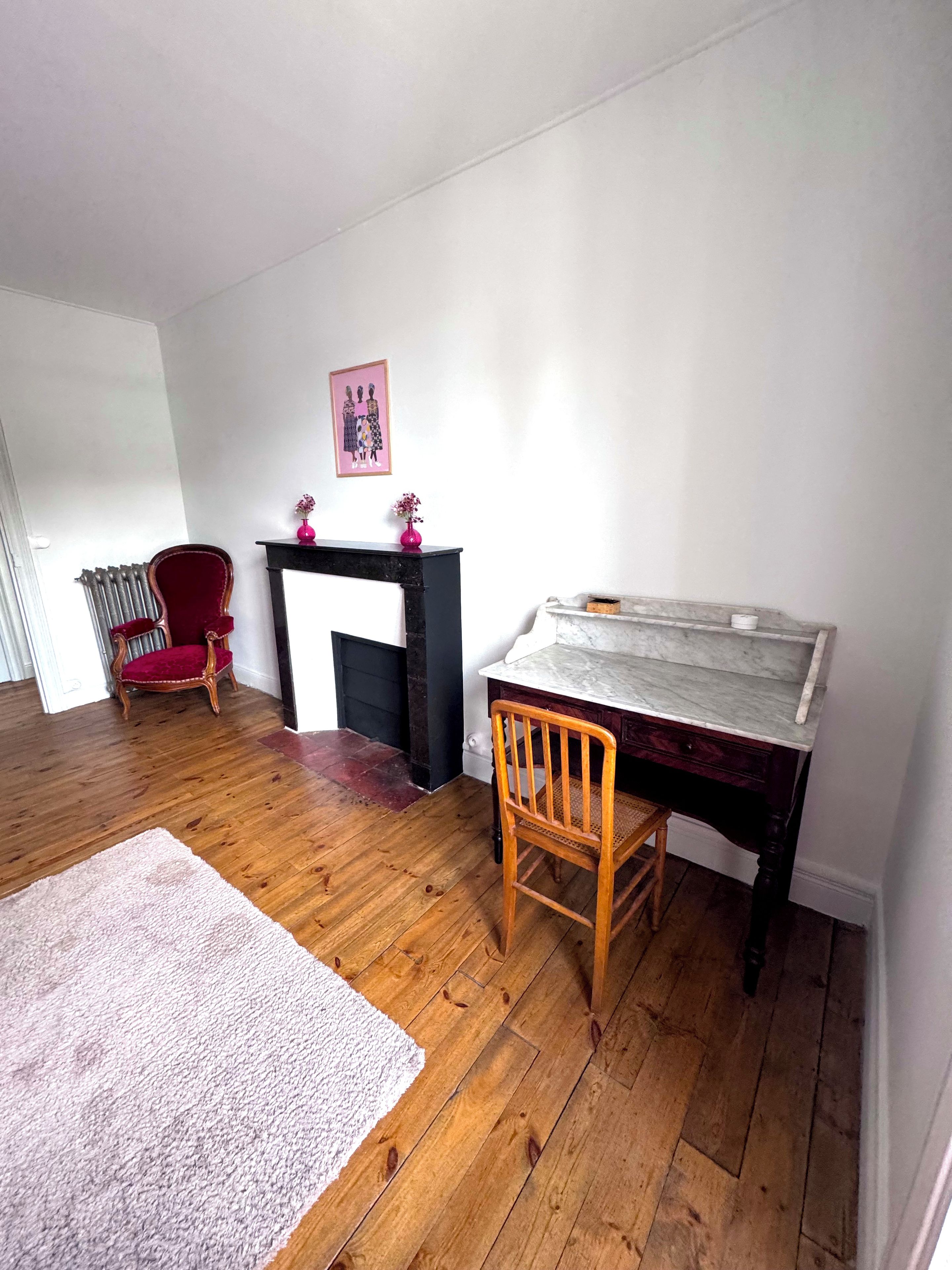 Ein Zimmer mit Kamin, einem Holzstuhl, einem Tisch und einer Heizung.