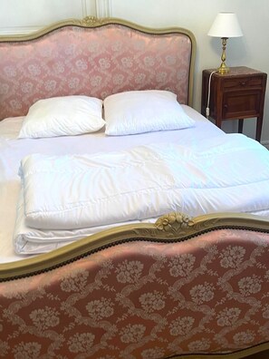 Un lit avec une tête de lit à motifs floraux et une literie blanche.