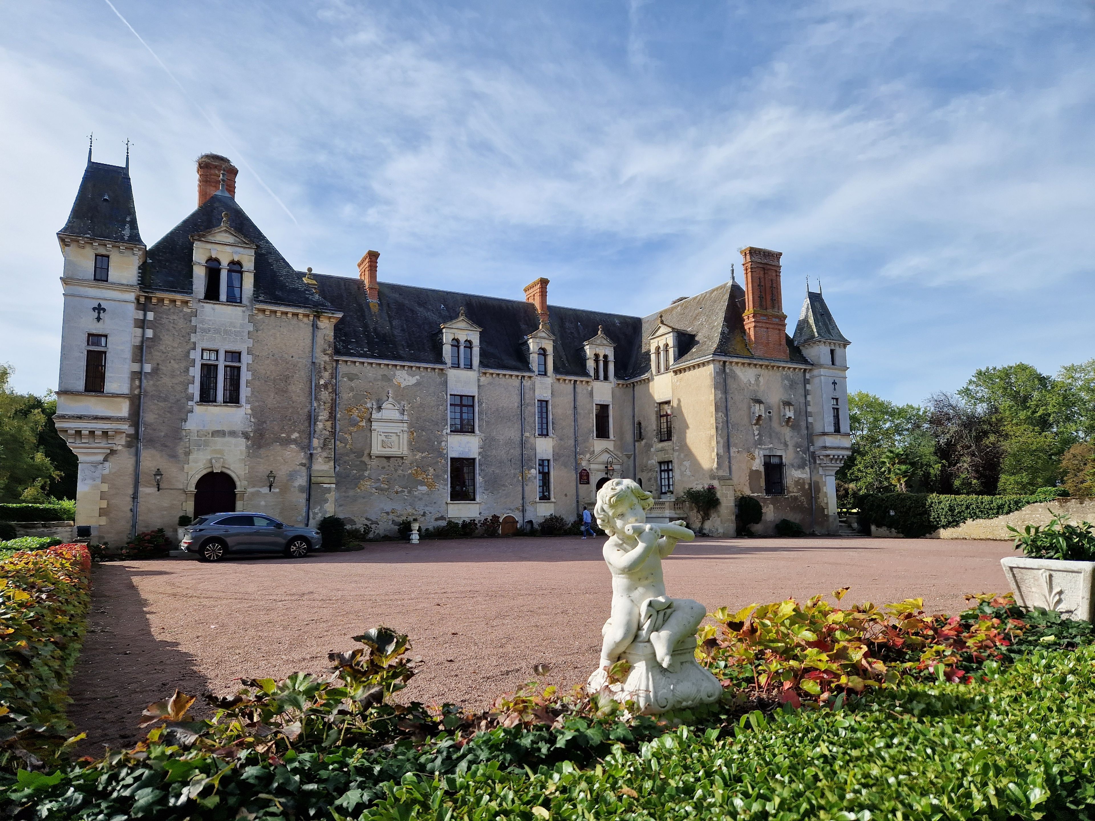 Ein historisches Gebäude mit Innenhof, Statue und einem geparkten Auto davor.