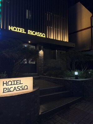 Um edifício com uma placa que diz 'HOTEL PICASSO' e uma placa menor abaixo.