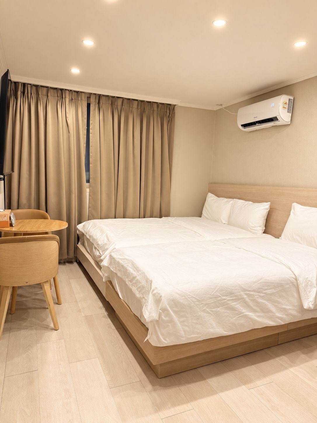 Une chambre d’hôtel équipée d’un lit, d’un bureau, d’une chaise, d’un climatiseur et de rideaux.