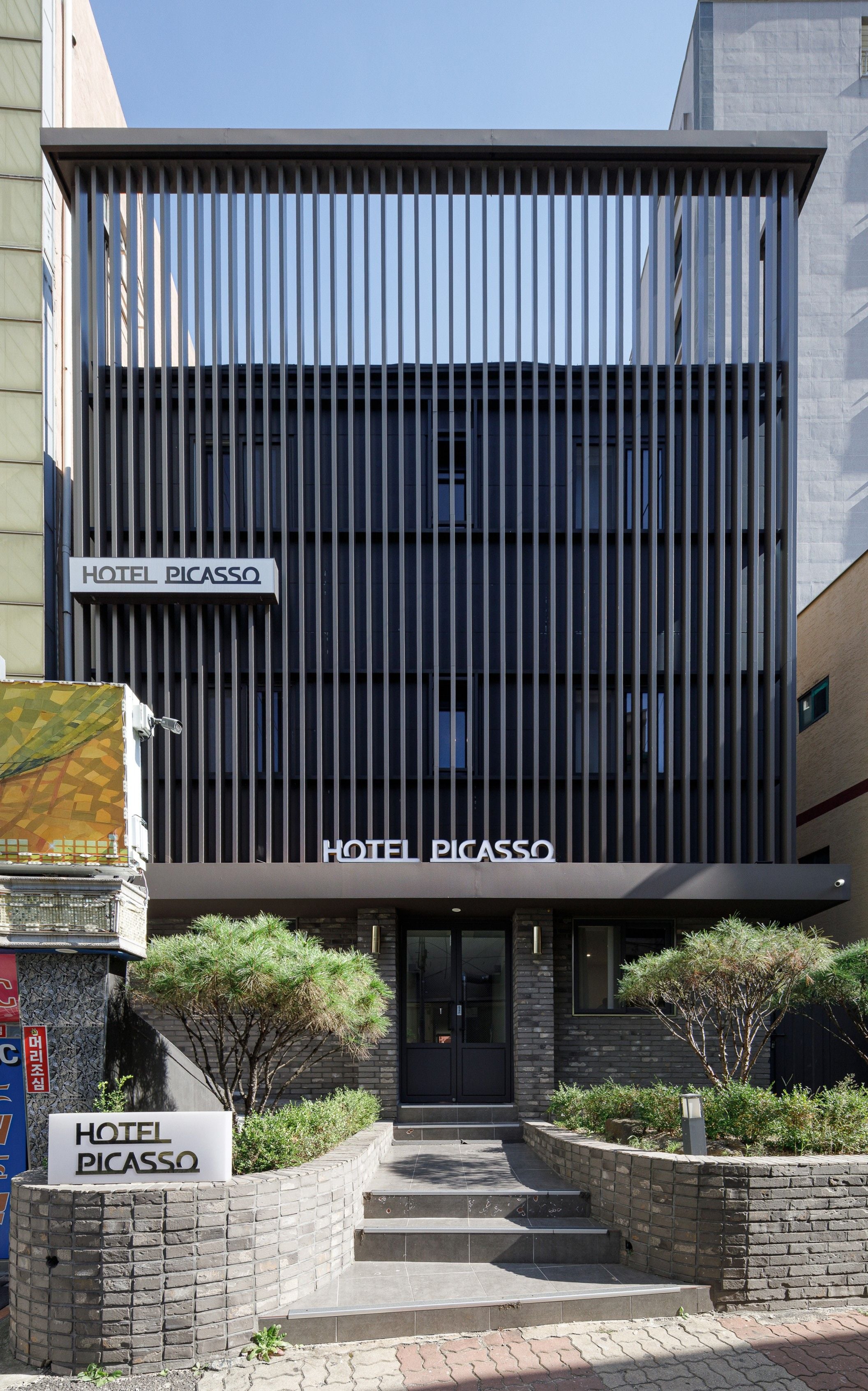 A modern building with a sign reading 'HOTEL PICASSO' at the entrance.