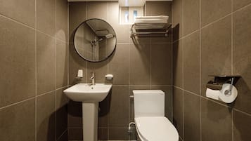 Ein modernes Badezimmer mit Waschbecken, Toilette und einem runden Spiegel.