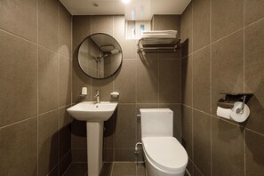 A modern bathroom with a sink, toilet, and a round mirror. - Hotel Picasso (Seoul)